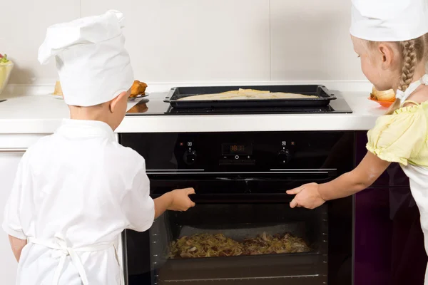 Jovens cozinheiros colocando suas pizzas no forno — Fotografia de Stock