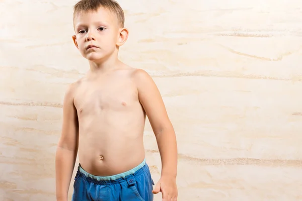 Mavi kısa pantolon üzerinde ciddi çocuk üstsüz — Stok fotoğraf
