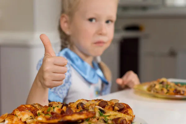 Маленька дівчинка насолоджується тарілкою домашньої піци — стокове фото
