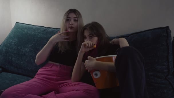 Δύο νεαρές γυναίκες κοιτάζουν με γοητεία μια οθόνη τηλεόρασης. — Αρχείο Βίντεο