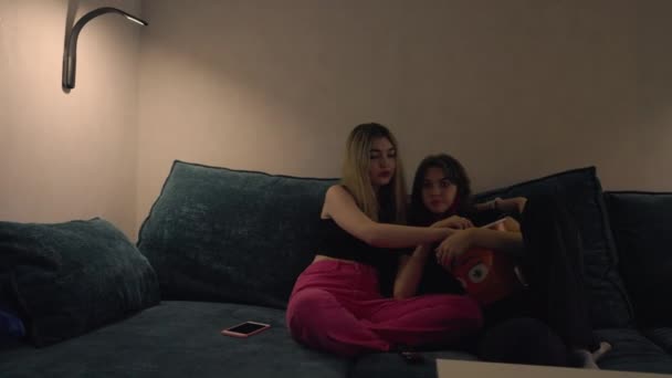 Twee jonge vrouw snacken op popcorn op een comfortabele bank — Stockvideo