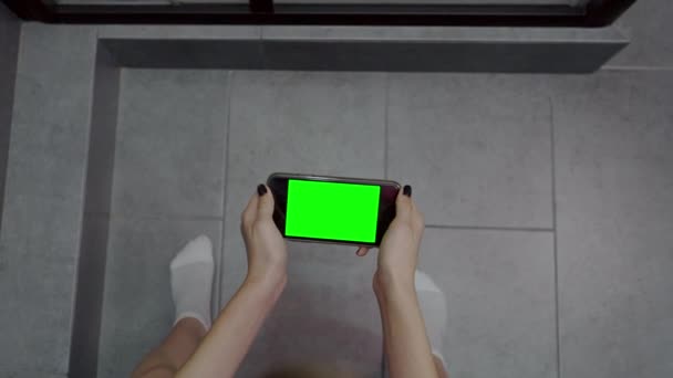 Mujer sentada en un inodoro usando su teléfono móvil — Vídeos de Stock