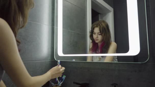 Reflexión en el espejo de una joven lavándose los dientes — Vídeos de Stock