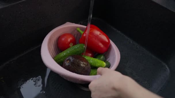 Женщина стирает различные свежие ингредиенты салата под краном — стоковое видео