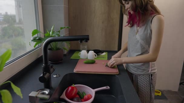 Aantrekkelijk jong tiener meisje voorbereiding van een frisse groene salade — Stockvideo