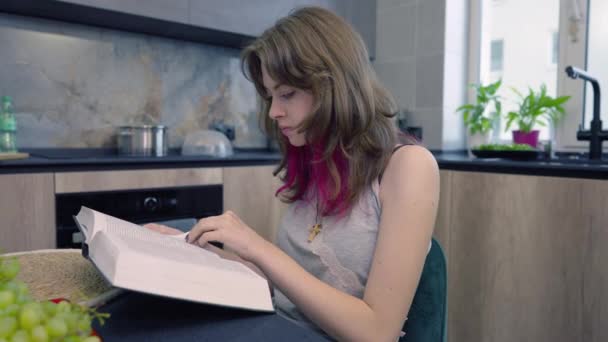Jonge vrouw die zit te lezen of studeren uit een groot boek — Stockvideo