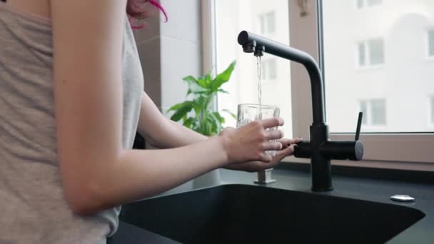 Frau gießt ein Glas Wasser aus dem Küchenhahn — Stockvideo