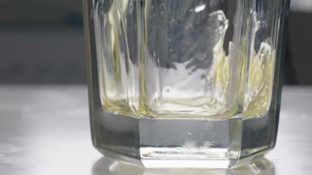 Onderkant van het glazen uitzicht op bier dat in de tuimelaar stroomt — Stockvideo