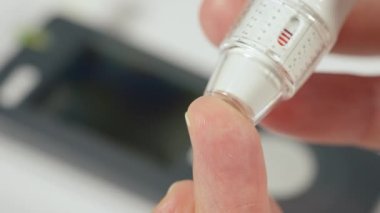 Kan şekeri ölçümü yapan bir adam kitte kan şekeri ölçümü yapıyor.