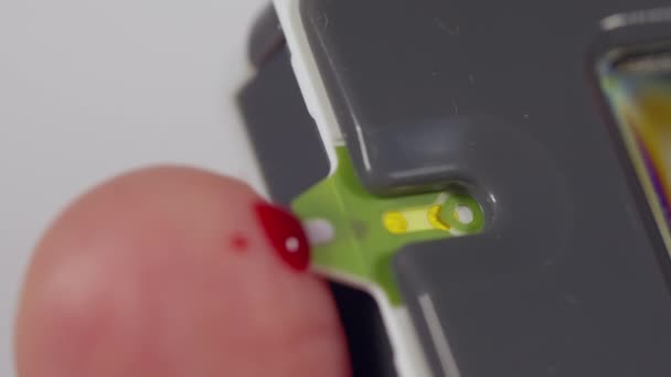 Hombre usando un glucosímetro después de pincharse el dedo por sangre — Vídeos de Stock