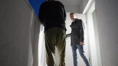 İki adam açık bir kapıda alışveriş yapıyor.