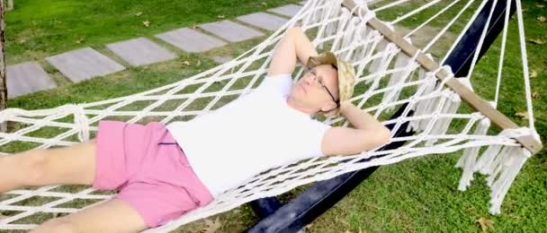 公園のハンモックの上で太陽の下で寝そべっている中年の男 — ストック動画