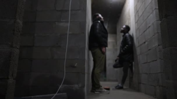 Vit kille och svart kille står i en källare — Stockvideo