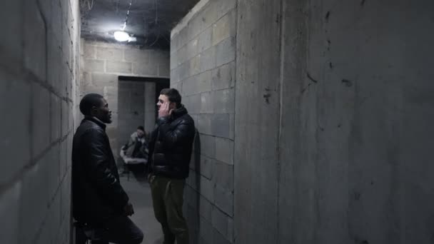 Blick in einen Keller mit Menschen, die sich während des Bombardements versteckt halten — Stockvideo