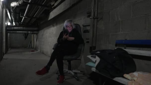 Frau sitzt auf einem Stuhl und liest in einem Luftschutzbunker Kriegsnachrichten — Stockvideo
