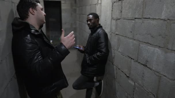 Caucásico chico y negro chico están de pie en un refugio a prueba de bombas durante un bombardeo — Vídeo de stock
