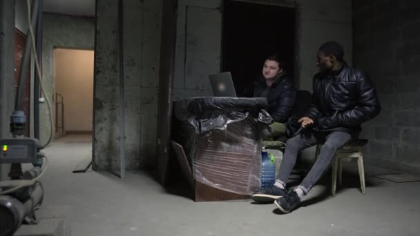 Kaukasier und Schwarzer verstecken sich während eines Krieges in einem Keller — Stockvideo