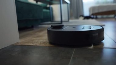 Düşük açılı bir evin ahşap zemininde, modern programlanabilir uzaktan kumandalı elektrikli süpürge.
