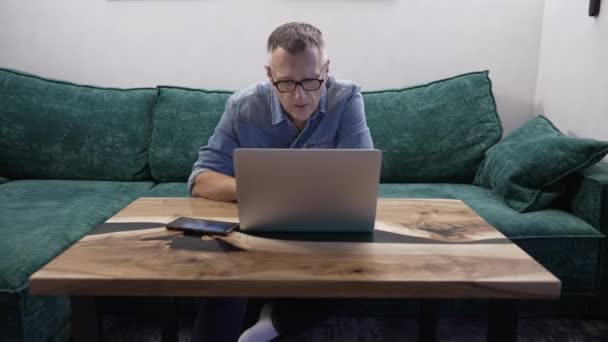 Mężczyzna Średnim Wieku Siedzi Zielonej Sofie Podczas Korzystania Laptopa Celów — Wideo stockowe