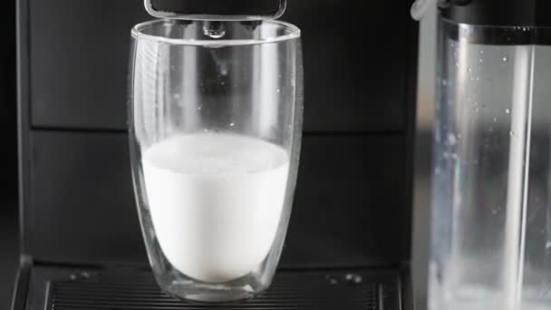 Frothed milk being dispensed into a glass by a coffee machine — Stockvideo