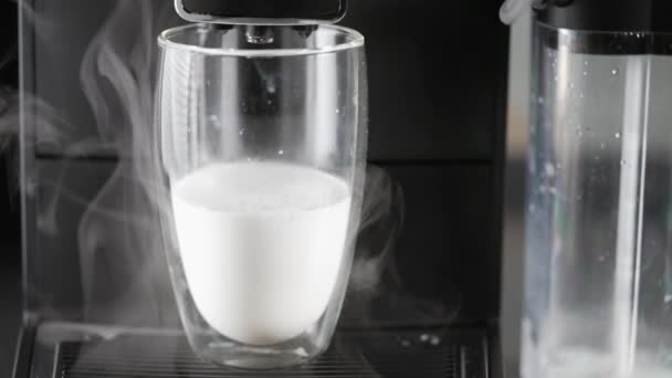 Glass half filled with hot milk poured from a coffee machine — Stockvideo