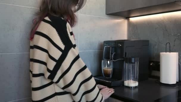 Young woman preparing a hot drink at the coffee machine — Video