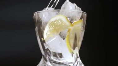 Alkollü bir içeceği buzlu bardağa doldurmak ve taze limon dilimlemek.