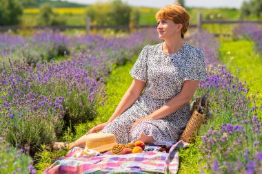 Woman spending a relaxing day in a field of lavender enjoying a healthy picnic with fresh fruit
