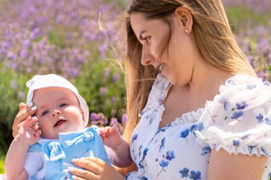 Young mother watching her happy gurgling baby boy cradled in her arms in a close up portrait