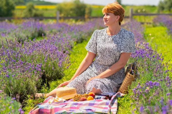 Woman spending a relaxing day in a field of lavender enjoying a healthy picnic with fresh fruit