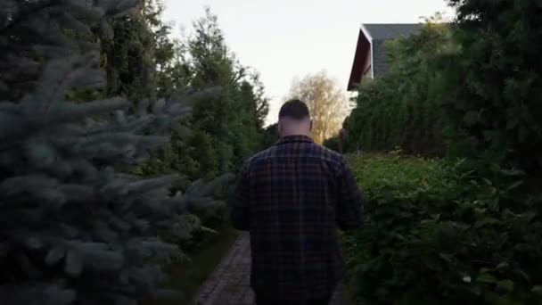 Man Walking Away Green Shrubs Dusk Head Bowed Distant House — Stock Video