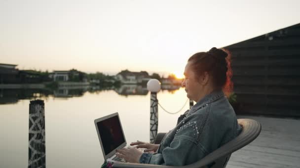 Stílusos Gépelés Laptopján Napnyugtakor Szabadban Egy Fedélzet Felett Egy Nyugodt — Stock videók