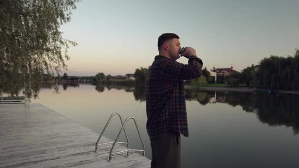Giovane Uomo Piedi Bere Caffè Ponte Legno Che Affaccia Tranquillo — Video Stock