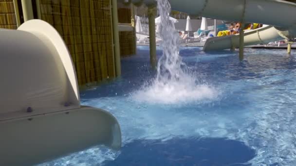 根据旅游理念 水从游乐场或酒店度假胜地的滑道上滑落下来 滑向下面闪闪发光的蓝色游泳池 — 图库视频影像