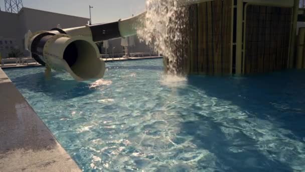 夏休みのコンセプトで休日のリゾートで日光浴プールに水のスライドの出口で水しぶきをカスケード — ストック動画