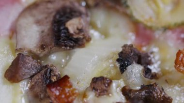 Close up detail of freshly baked ham and mushroom Italian pizza topped with melted mozzarella cheese in a full frame view