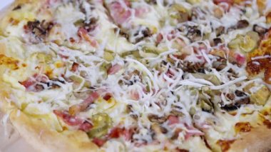 İtalyan jambonu ve turşulu mantarlı pizza ve ekstra rendelenmiş mozzarella peyniri. Menü reklamcılığı veya fast food kavramları için yüksek açılı bir görünüm.