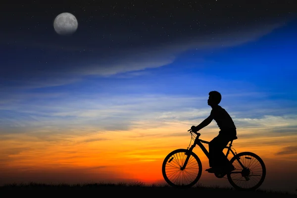 Силуетний хлопчик їде на велосипеді на заході сонця — стокове фото