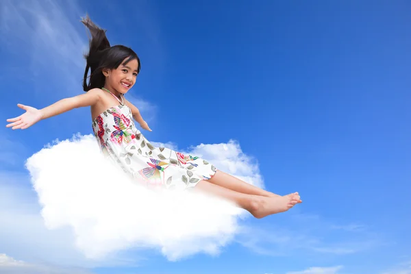 Smiling little girl sitting on the cloud over sky — Stock Photo, Image