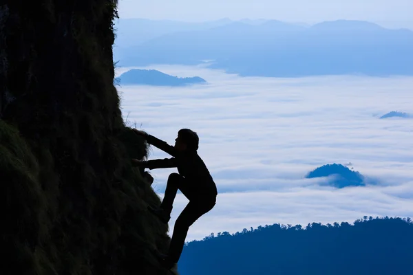 Un homme d'affaires de Sihouette grimpe une montagne — Photo