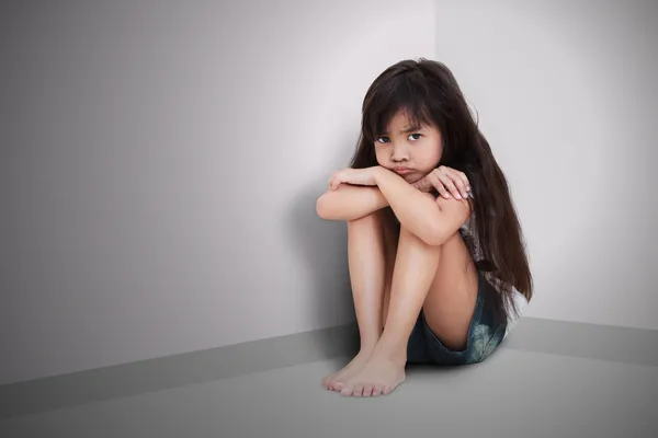 Sad little girl sitting on the floor — Stock Photo, Image