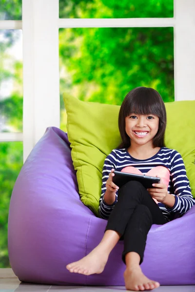 Pequeña chica asiática jugando con la tableta ordenador en casa en casa — Foto de Stock