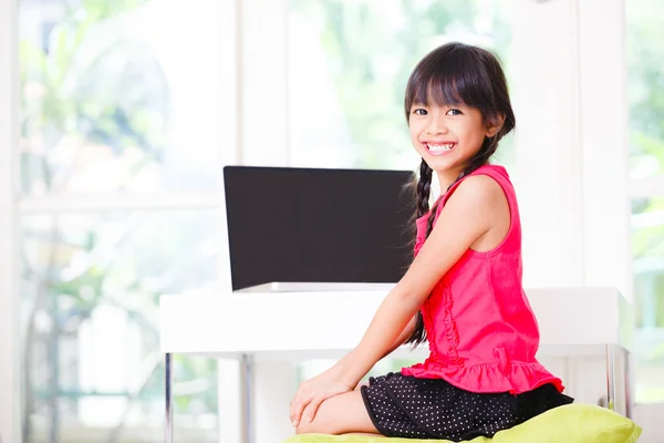 Pequeña chica asiática con ordenador en casa — Foto de Stock