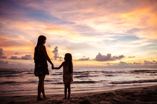 Moeder en kind silhouetten op zonsondergang strand — Stockfoto