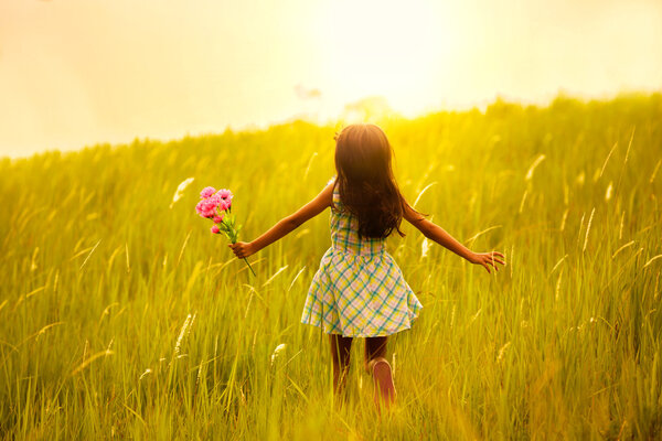 Маленькая девочка бежит по лугу с закатом
