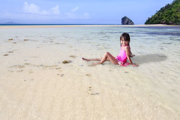 Tropik sahilde oturup küçük Asyalı kız — Stok fotoğraf