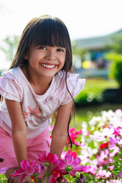 Asiatiska liten flicka står med händerna på knäna på en äng, utomhus — Stockfoto