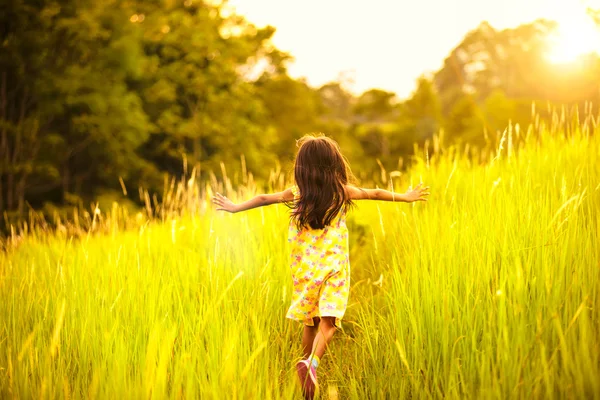 Niña corriendo en el prado con puesta de sol — Foto de Stock