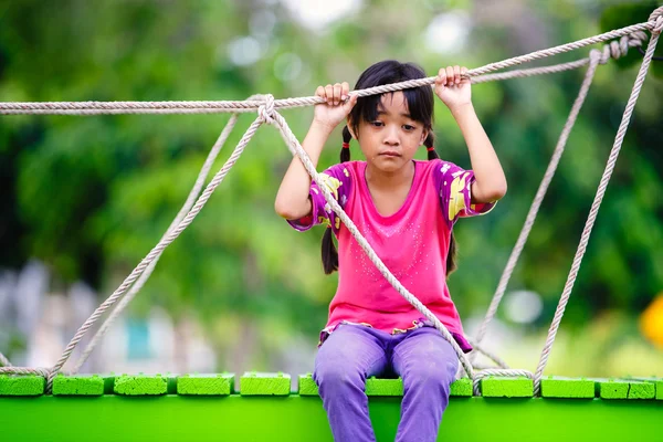 Piangendo piccola ragazza asiatica seduta da sola su un parco giochi — Foto Stock