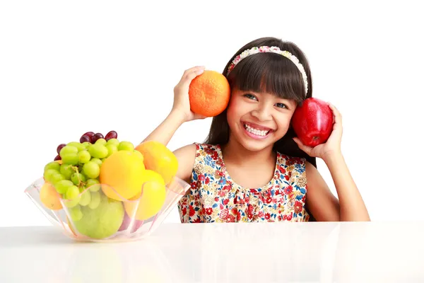 과일 접시와 함께 테이블에 앉아 행복 한 작은 아시아 소녀 — 스톡 사진